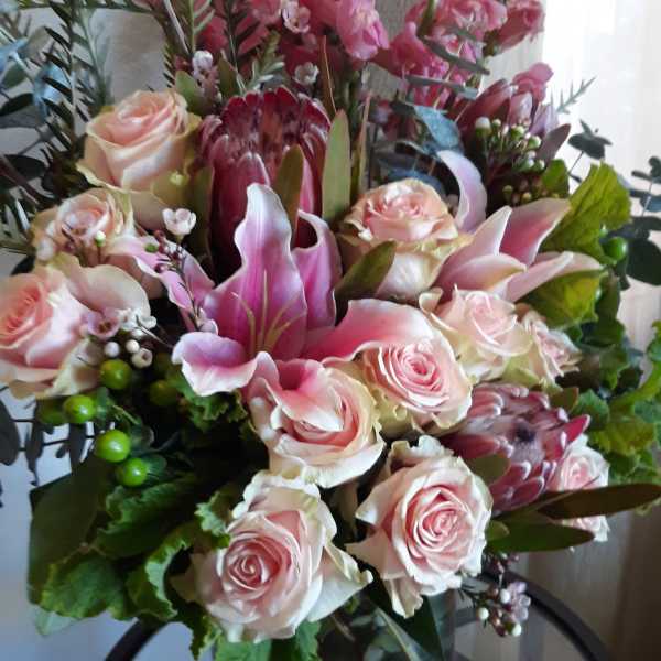 Pink roses and lilies arranged in a glass vase