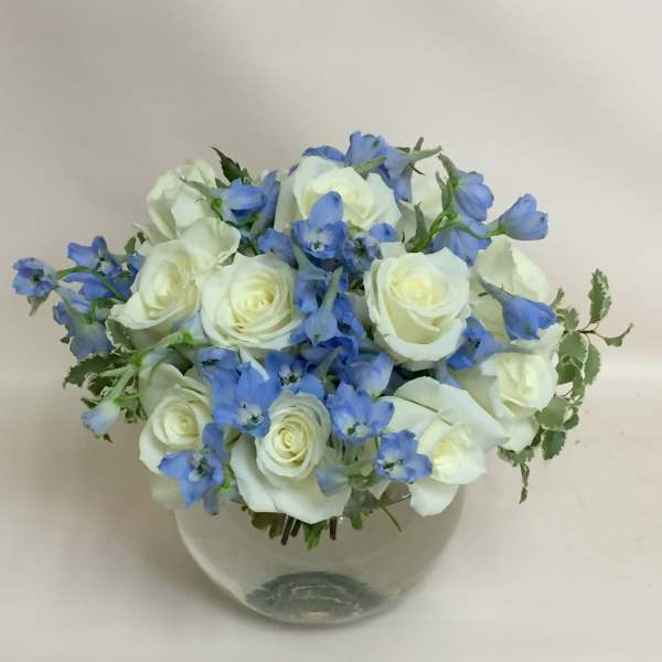 White roses and blue flowers in a clear glass vase
