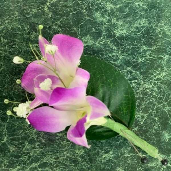 Pink and white calla lily corsage on a green marbled background