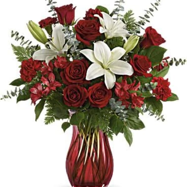 Red roses and white lilies in a red glass vase