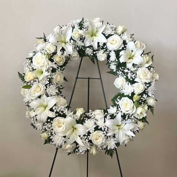 White floral wreath on a black stand