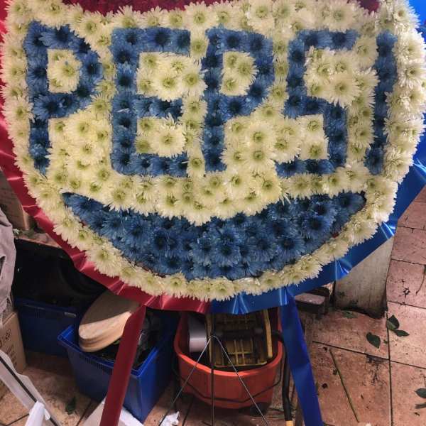Large floral wreath with the word PEPSI in blue and white flowers
