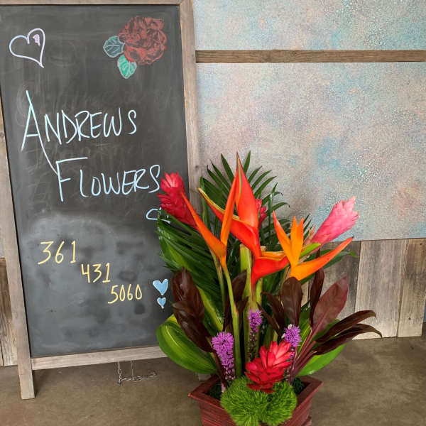 Tropical flower arrangement in a wooden box with orange and pink blooms