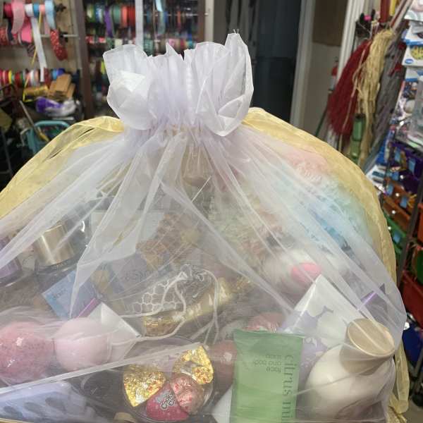 Gift basket wrapped in sheer tulle with assorted treats and candles