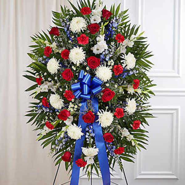 Standing funeral wreath with red and white flowers and a blue ribbon