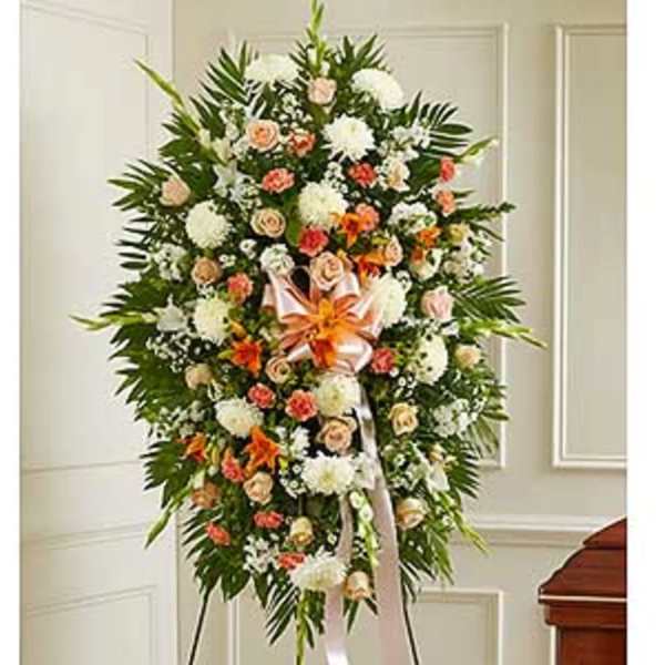 Standing funeral spray with white, peach, and orange flowers on a ribboned easel