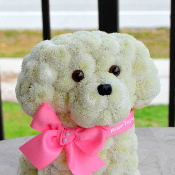 White flower-covered dog figure with a pink bow