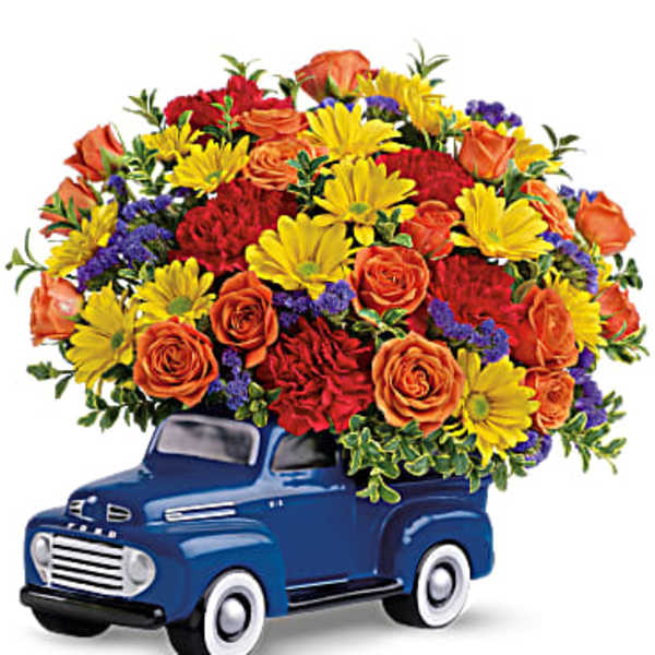 Bouquet of orange roses, yellow daisies, and red carnations in a blue truck container