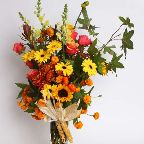 Tall autumn bouquet in a clear glass vase with yellow and orange flowers