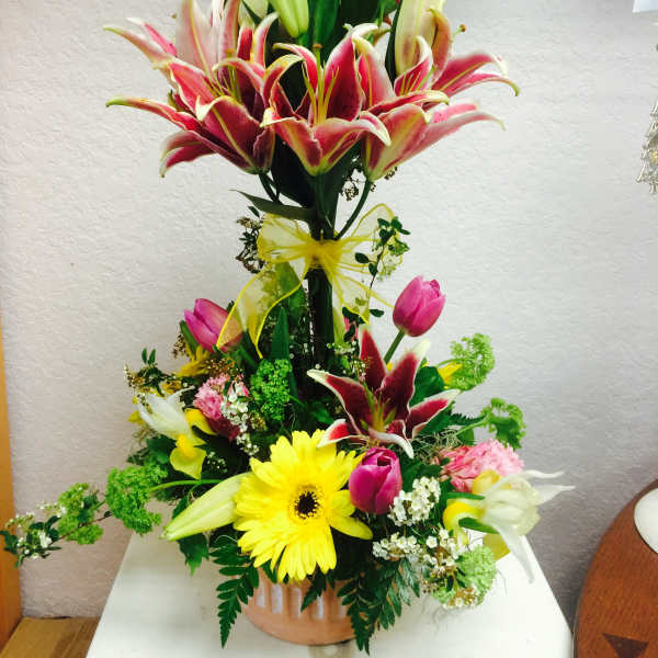 Tall mixed bouquet with lilies, tulips, and a yellow gerbera daisy in a vase