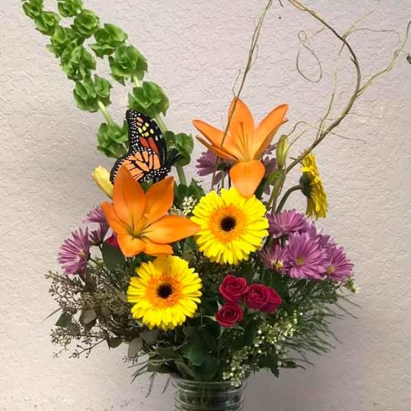 Colorful mixed bouquet in a glass vase with orange lilies and yellow daisies