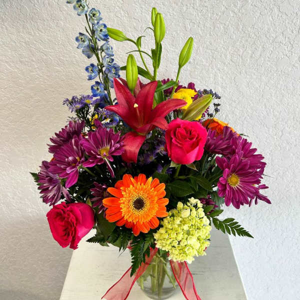 Mixed bouquet in a glass vase with lilies, roses, and daisies