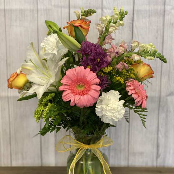 Mixed bouquet in a glass vase with a yellow ribbon