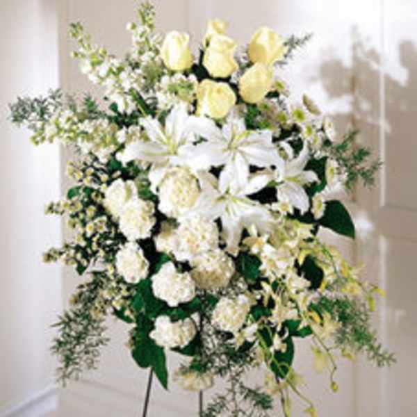 Standing spray of white lilies and pale yellow roses on a metal easel
