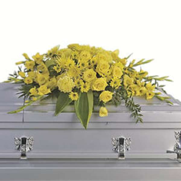 Yellow floral casket spray on a gray casket