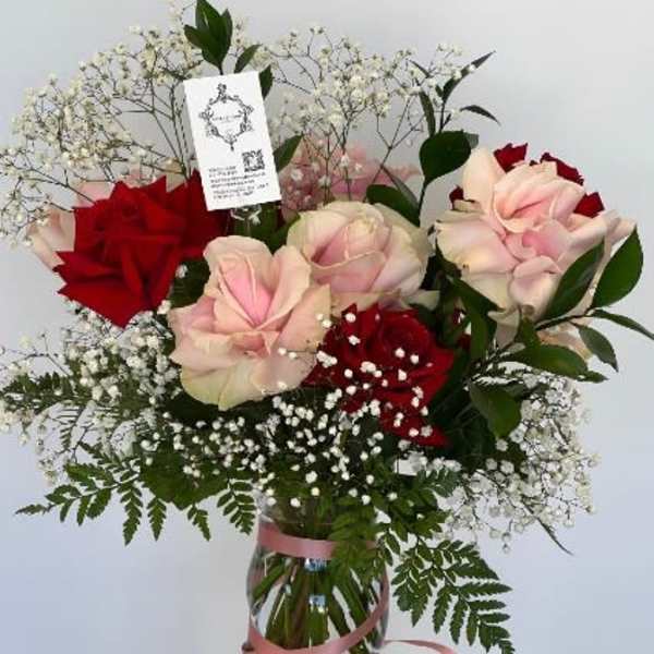 Pink and red roses in a glass vase with baby's breath
