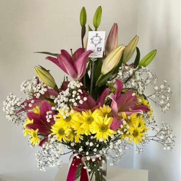 Bouquet of pink lilies and yellow daisies in a glass vase