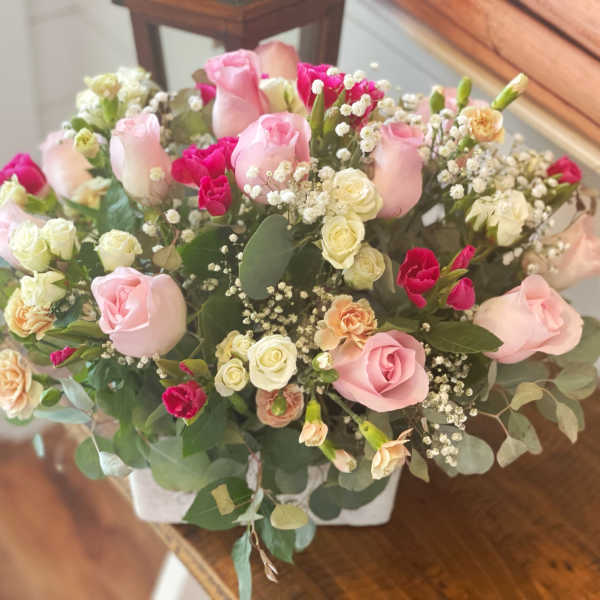 Pink and white rose bouquet in a white container