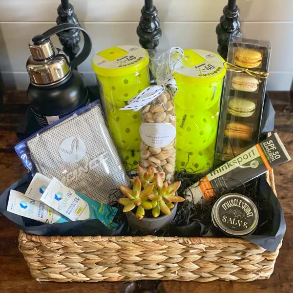 Gift basket with water bottle, snacks, macaron box, and a small succulent