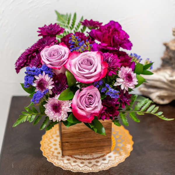 Pink roses and purple flowers arranged in a wooden box