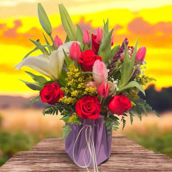 Bouquet of red roses, pink tulips, and white lilies in a purple box