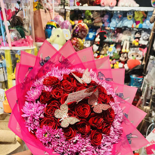 Bouquet of red roses and pink daisies wrapped in bright pink paper