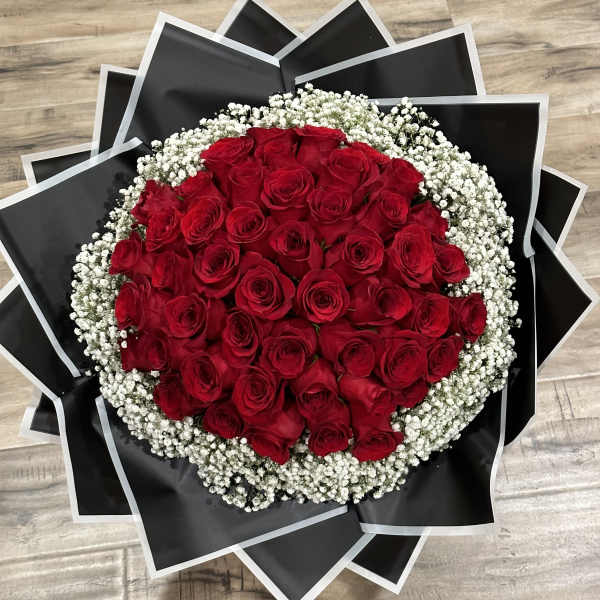 Round bouquet of red roses with white baby's breath in black wrap