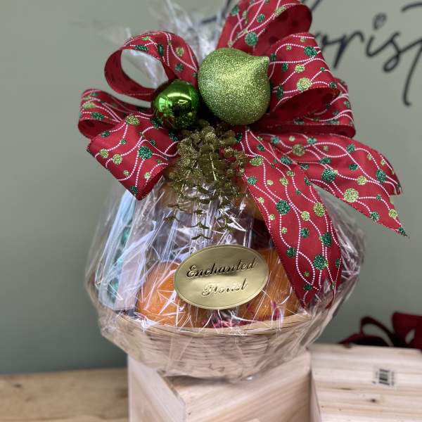 Gift basket wrapped in clear plastic with a large red holiday bow