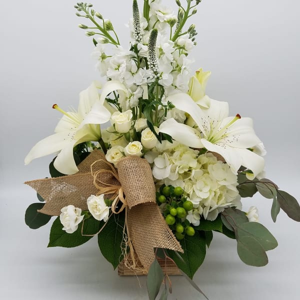 White lilies and roses arranged in a burlap-wrapped box