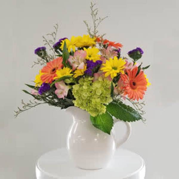 Colorful mixed bouquet in a white pitcher vase