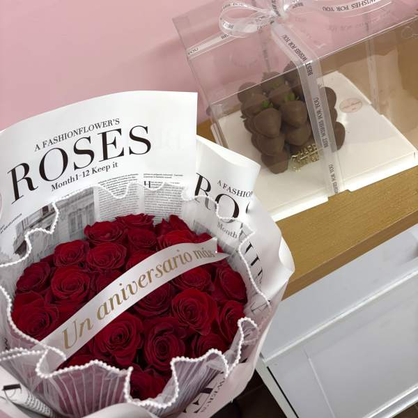 Bouquet of red roses in pink and white wrapping beside a clear gift box of chocolates