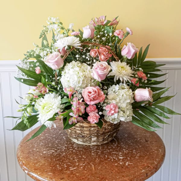 Pink and white mixed flower arrangement in a wicker basket