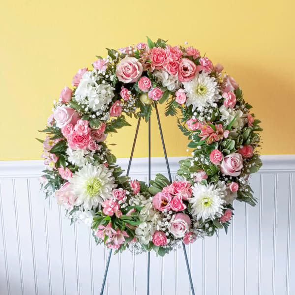 Pink and white floral wreath on a metal stand
