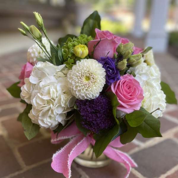 Bouquet of pink and white flowers in a small vase with a pink ribbon