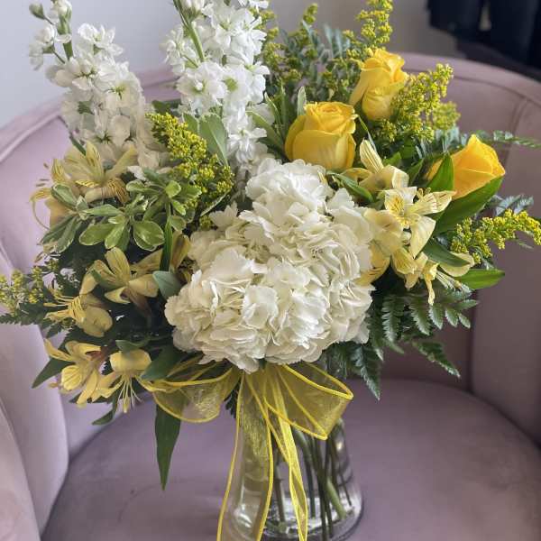 Bouquet of white and yellow flowers in a clear glass vase