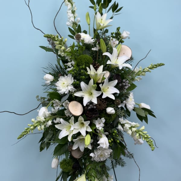Tall white floral standing spray with lilies and mixed blooms on a frame