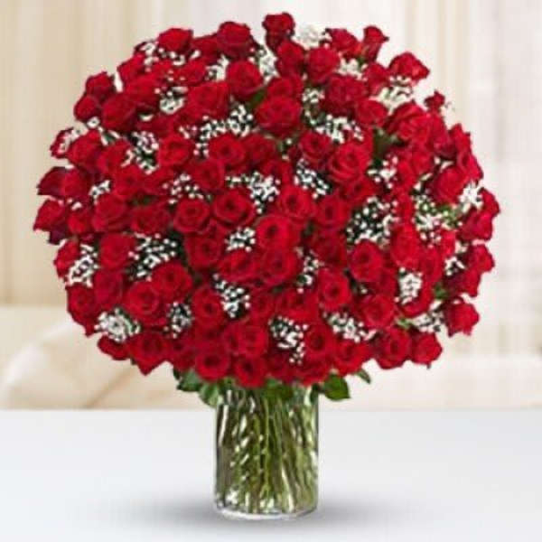 Large bouquet of red roses with white filler flowers arranged in a clear glass vase