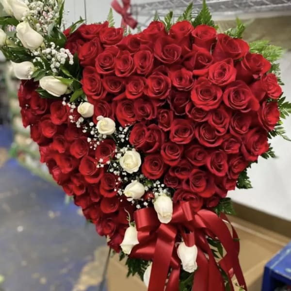 Heart-shaped bouquet of red and white roses with a red ribbon