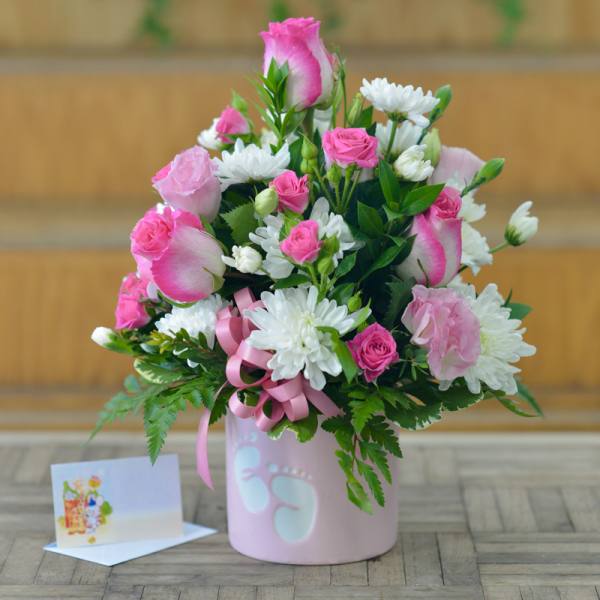 Pink and white bouquet in a pastel pink vase with a ribbon