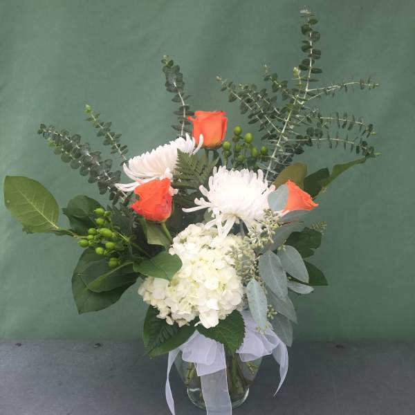 Bouquet of orange roses, white chrysanthemums, and white hydrangea in a glass vase