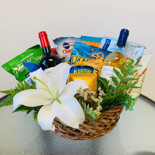 Gift basket with wine, snacks, and a white lily
