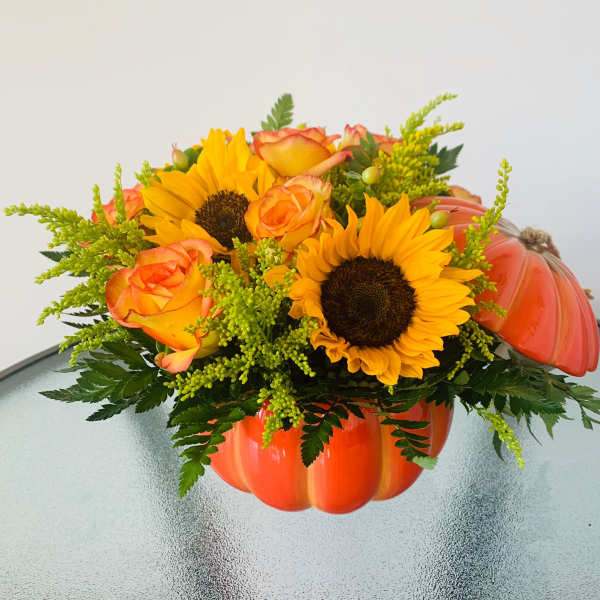 Sunflowers and orange roses in a pumpkin-shaped container