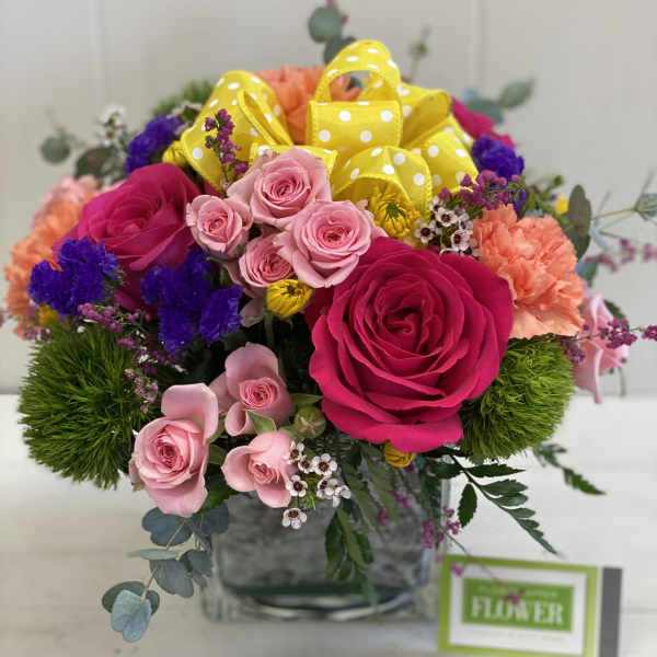 Bouquet of pink and magenta roses with yellow polka-dot ribbon in a glass vase