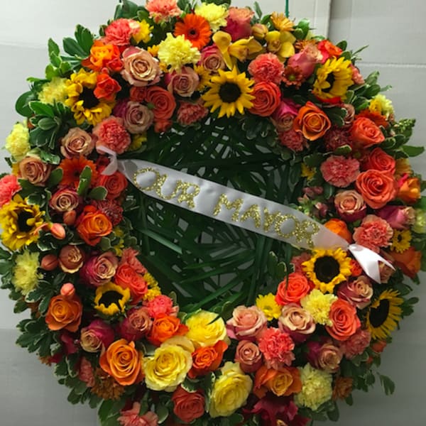 Large floral wreath with a white ribbon reading "OUR MAYOR"