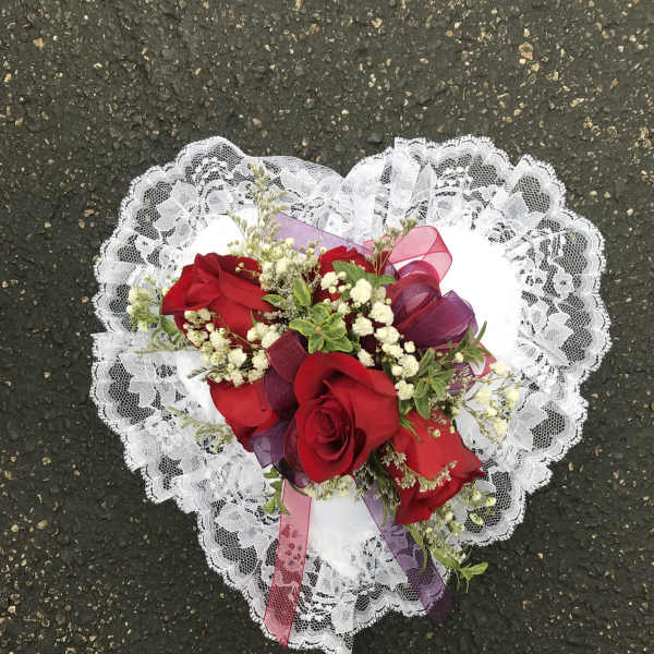 Heart-shaped bouquet of red roses with white lace trim and ribbon