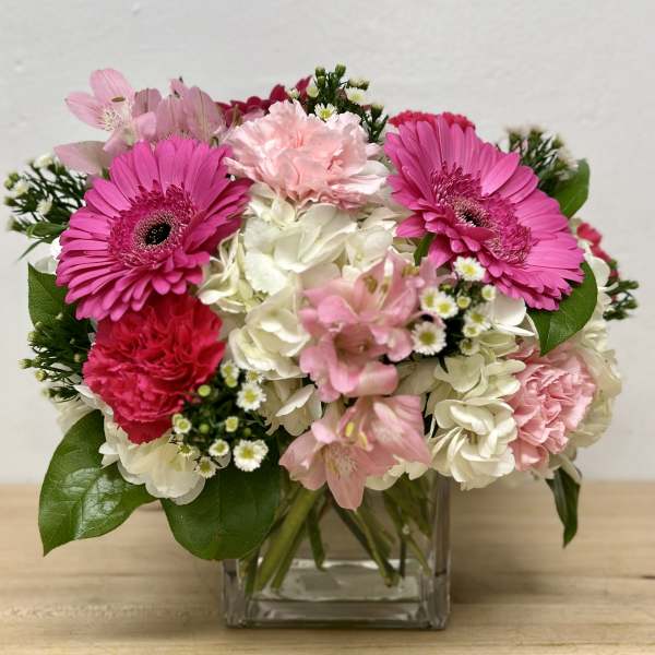 Pink gerberas and carnations in a clear glass vase