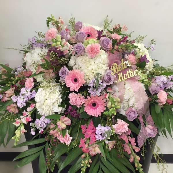 Large pastel floral arrangement with pink and lavender blooms in a black container