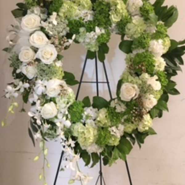 Heart-shaped floral wreath with white roses and green hydrangeas on an easel