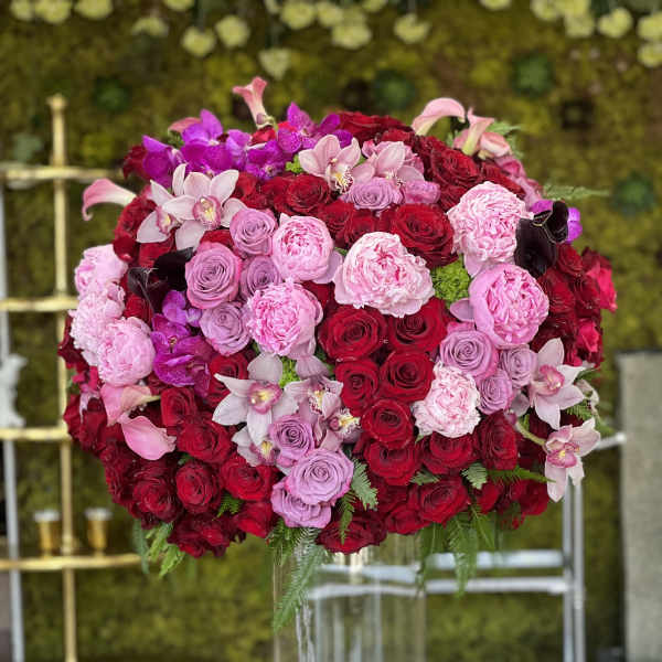 Large bouquet of red, pink, and purple flowers in a clear glass vase
