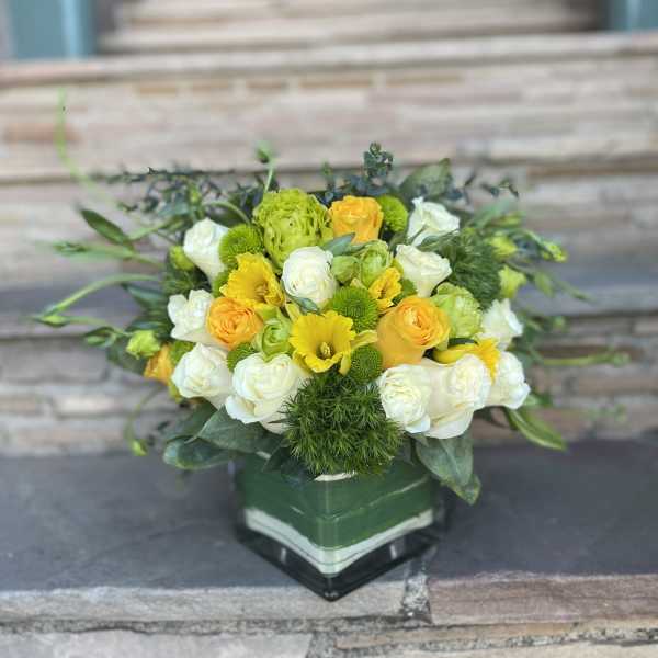 Yellow and white rose bouquet in a square glass vase